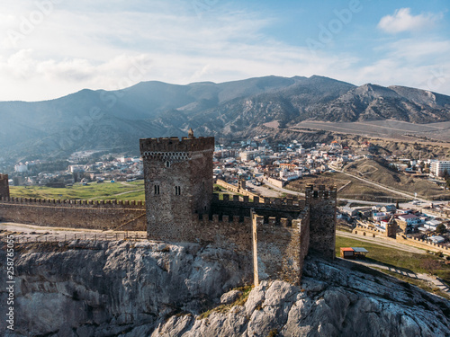 Ancient medieval Genoese fortress tower on mountain range rocks above sea, aerial view from drone to famous beautiful Crimean touristic landscape