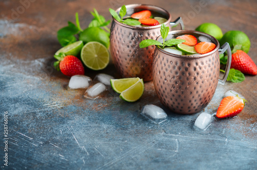 Wall Mural Moscow mule cocktail with ginger beer, vodka, lime, strawberries and mint in a cooper mugs