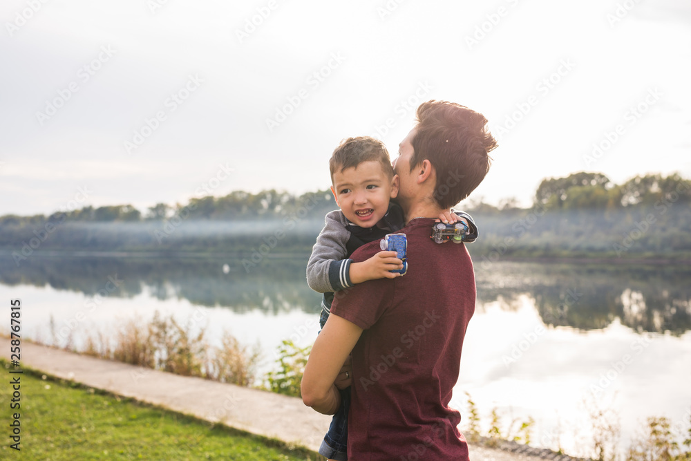 Fatherhood and children concept - Father holding his little son on nature Fatherhood and children concept - Father holding his little son on nature