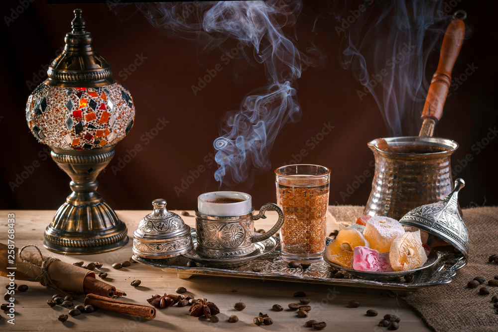 Turkish coffee in cezve and traditional Turkish delight. Steam over a cup. Antique lamp