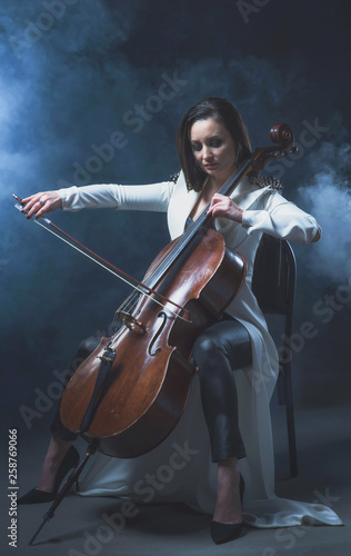 Beautiful woman in a white coat plays the cello © Антон Фрунзе