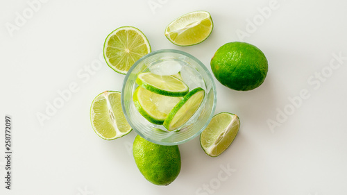 Woda z limonką w otoczeniu pokrojonej limonki na białym tle