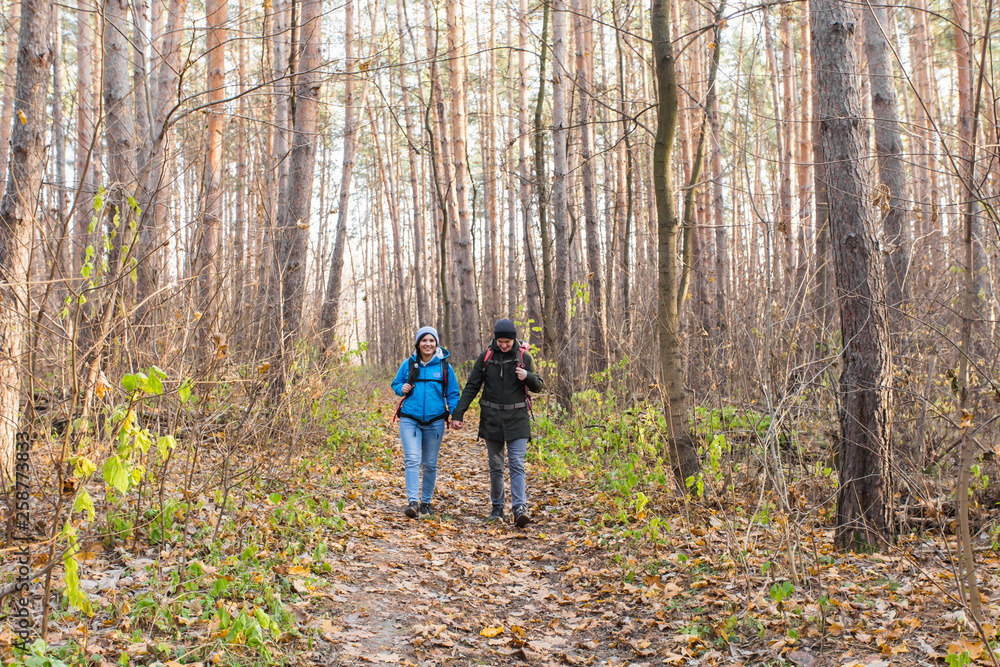 Travel, tourism, hike and people concept - tourists couple in autumn forest Travel, tourism, hike and people concept - tourists couple in autumn forest