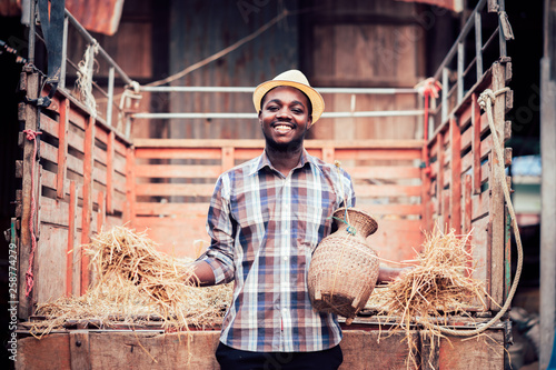 African farmer smiling and standing with small tractor on the countryside