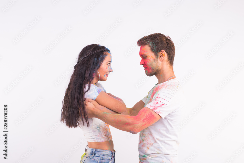 Holiday, social dance, holi and people concept - Happy couple having fun and dancing bachata or kizomba with multicolored powder on their faces on white background Holiday, social dance, holi and people concept - Happy couple having fun and dancing bachata or kizomba with multicolored powder on their faces on white background