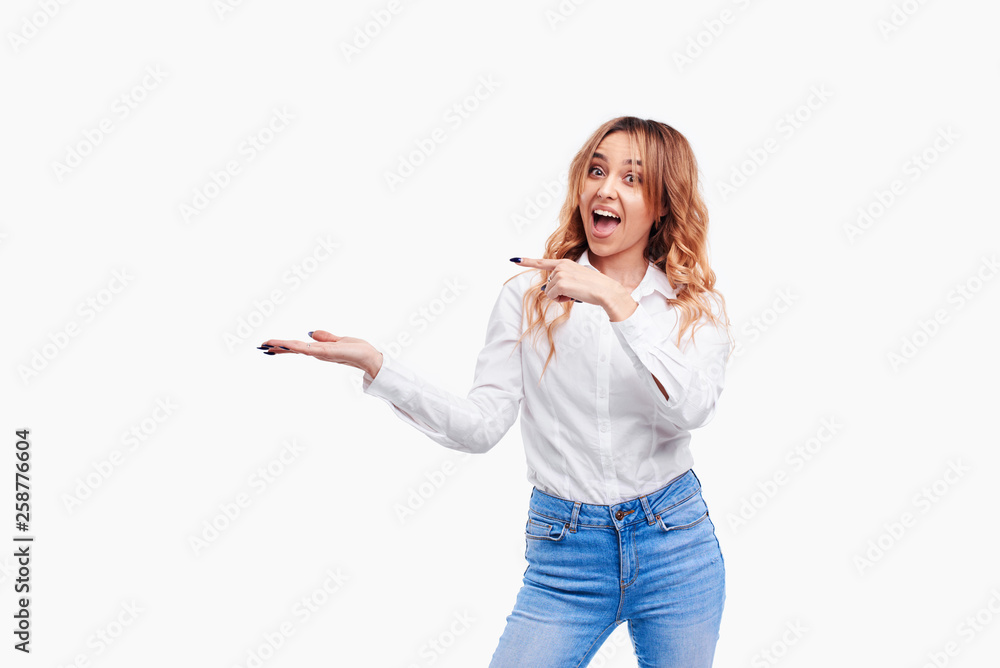 Happy surprised young female smiling broadly at camera, pointing fingers away, showing something interesting and exciting on white background with copy space for your text or advertising content Happy surprised young female smiling broadly at camera, pointing fingers away, showing something interesting and exciting on white background with copy space for your text or advertising content