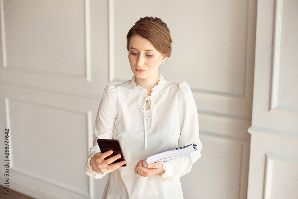Photo business woman wearing suit, looking smartphone and holding documents in hands. Photo business woman wearing suit, looking smartphone and holding documents in hands.