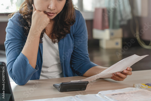 Asian woman calculating monthly expense and credit card debt.