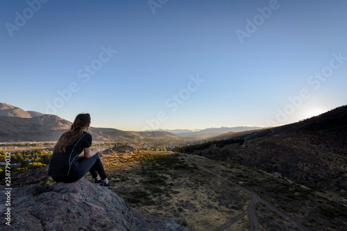 rear view of young woman in the mountains against alpenglow in the valley