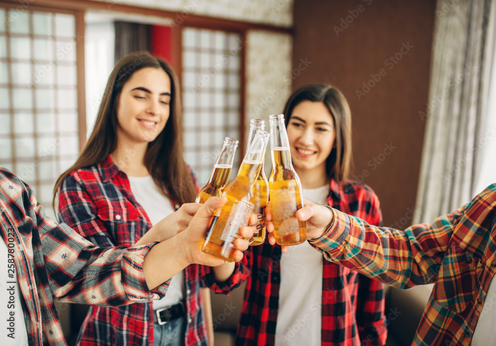 Friends clink bottles with beer at the home party Friends clink bottles with beer at the home party