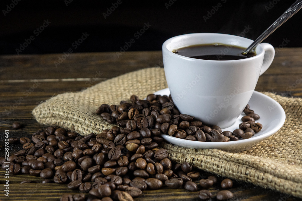 Cup of coffee and coffee beans on a rough wooden background. Cup of coffee and coffee beans on a rough wooden background.