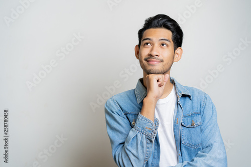 Asian man thinking and smiling.