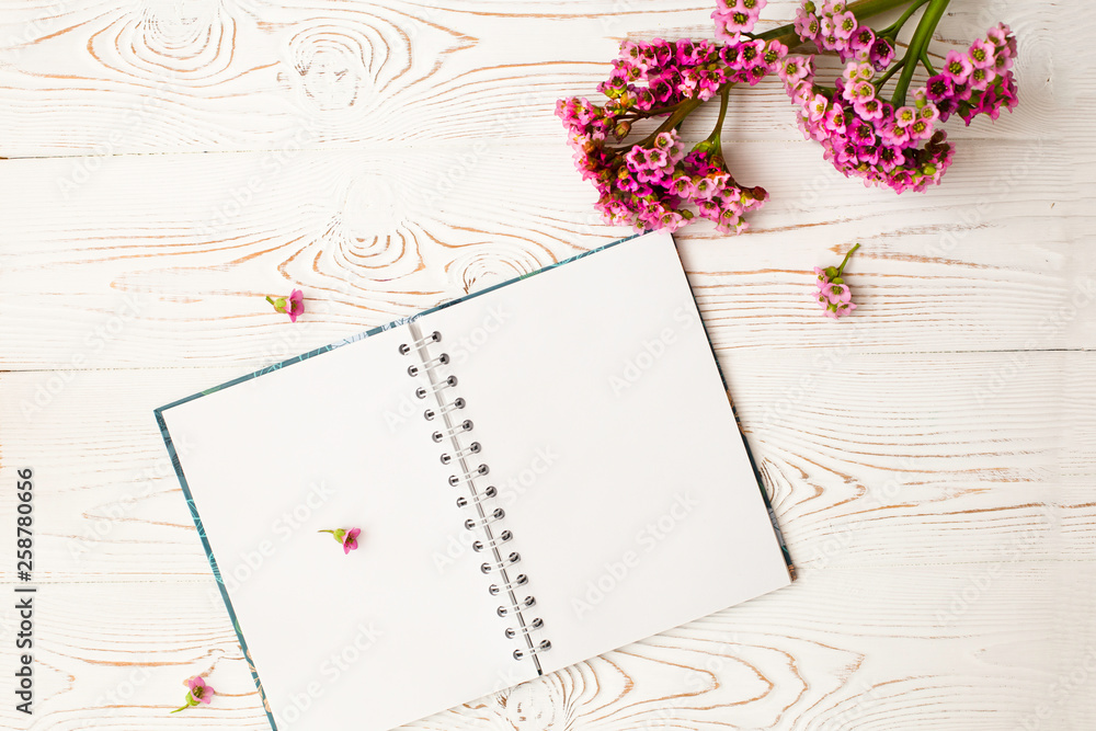 Naklejka premium Blank diary for your text and pink flower on a white wooden table. Flat design