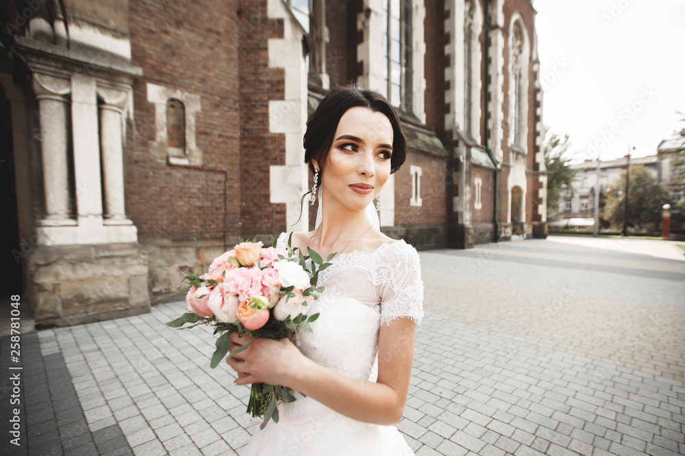 Fototapeta premium The bride on a walk near the wall of old gothic church