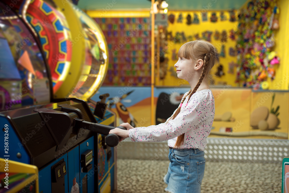 Little girl plays game machine, children center