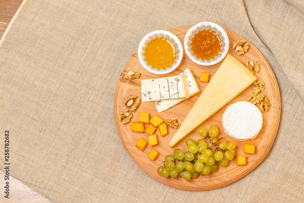 Fototapeta premium Assorted cheeses on round wooden board plate