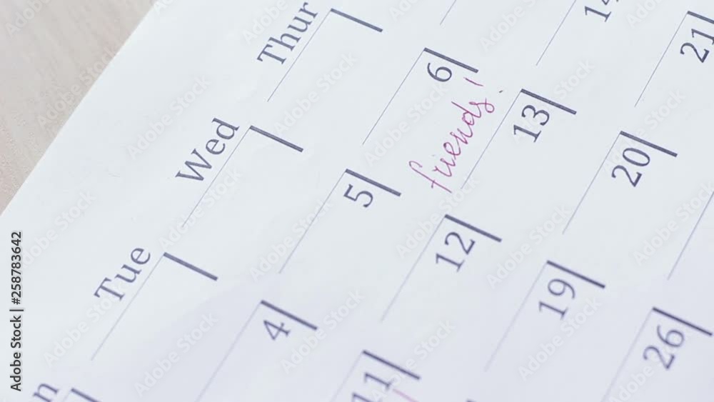 Male hand writes reminder of meeting with friends in the calendar Male hand writes reminder of meeting with friends in the calendar