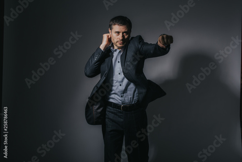 a business man in black suit puncing on a black background
