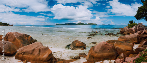 Tropical rockbound panorama landscape with white fluffy clouds above Praslin island. Anse Severe beach on La Digue island, Seychelles