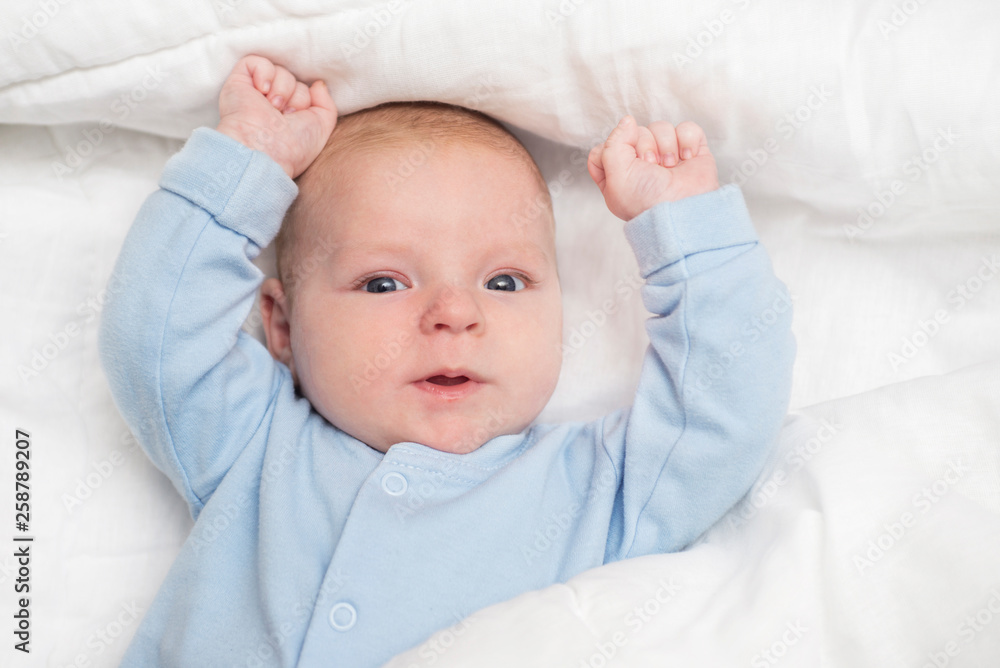 Portrait of a cute baby lying down on a bed. Baby on white cloth lying on his back Portrait of a cute baby lying down on a bed. Baby on white cloth lying on his back