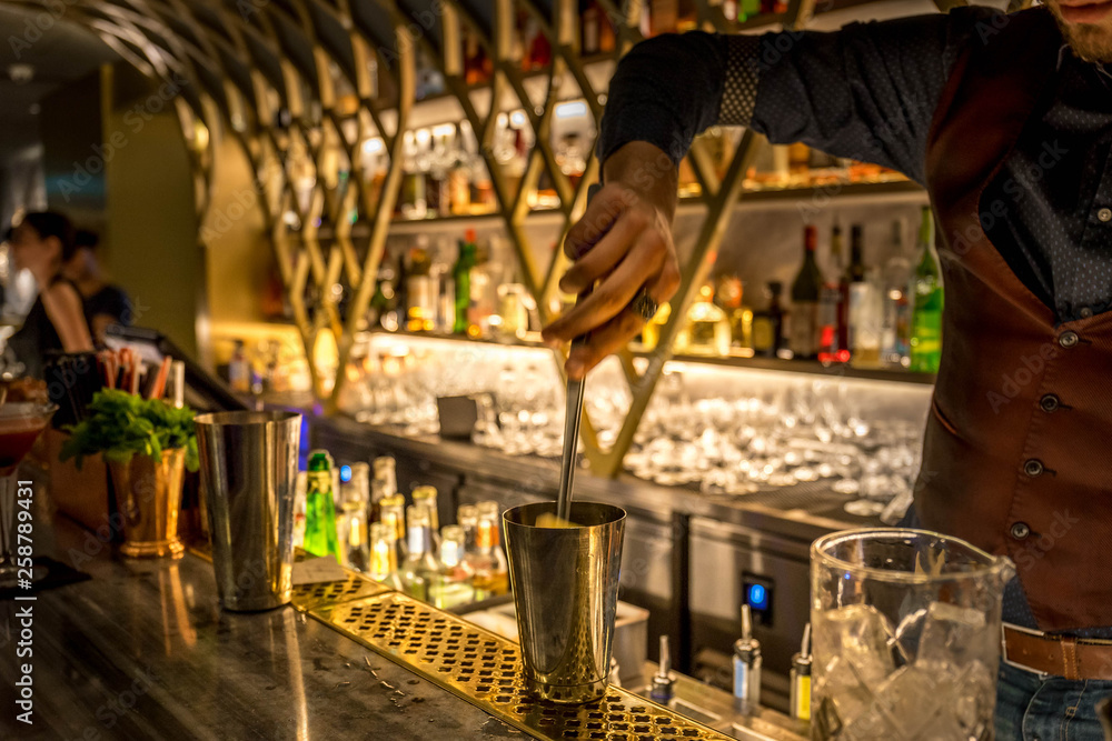 Obraz premium Barman preparing cocktails. Picture with blurry bar environment in the background.