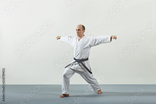 On a gray cover an adult male athlete performs formal karate exercises