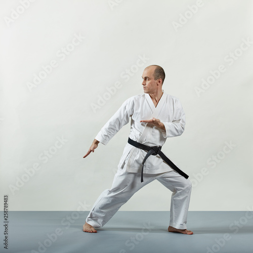 In karategi, a male athlete performs formal karate exercises on a gray background