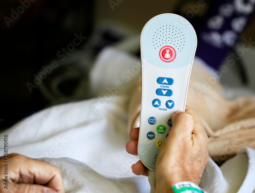 Old man holding TV remote with nurse call button