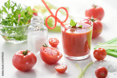 Tomato juice in glass with celery, cherry tomato, white wood background, closeup