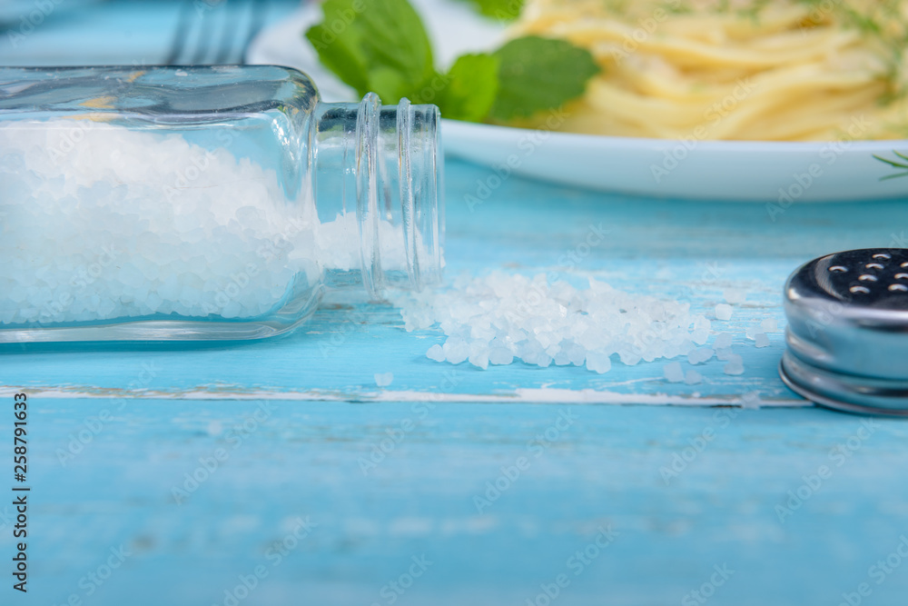 On the turquoise wooden table scattered salt close-up. On the turquoise wooden table scattered salt close-up.