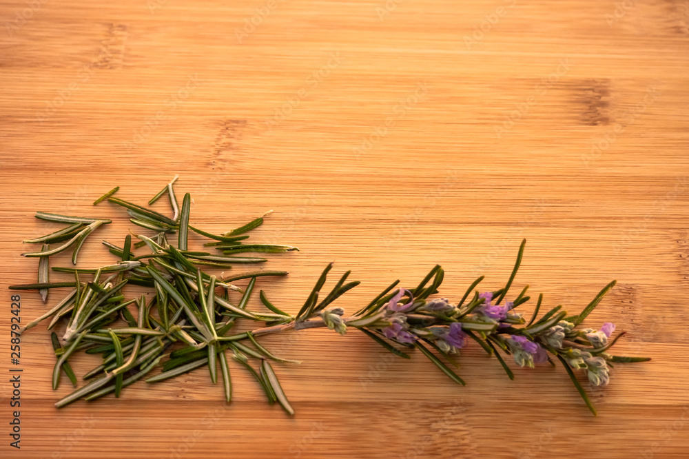 One rosemary blooming twig and rosemary leaves on a wooden table One rosemary blooming twig and rosemary leaves on a wooden table