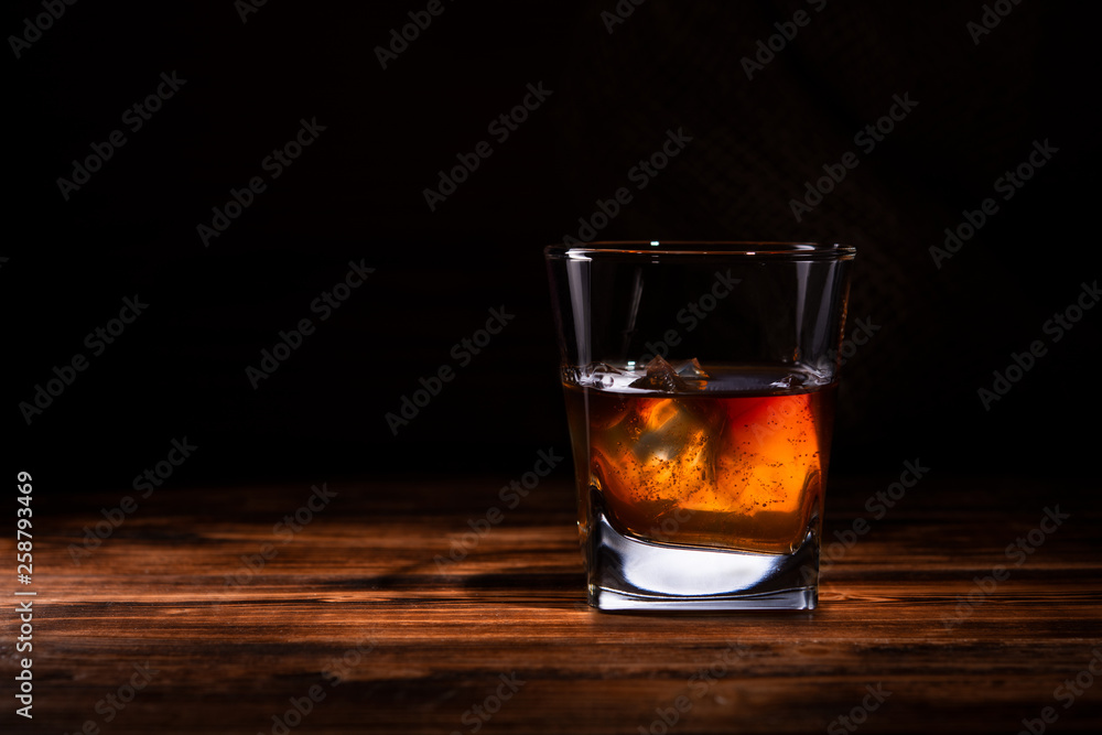 glass of whiskey or cognac on a wooden background