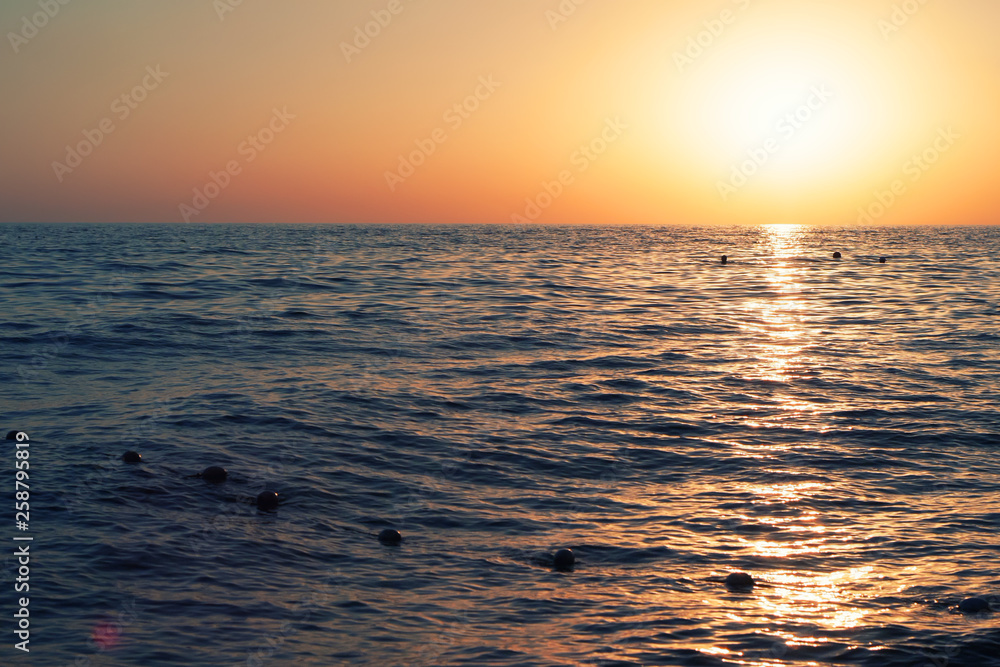 Bright sunset against the sky and the sea. Sunset on the beach. Beautiful sunset over a calm ocean or sea.