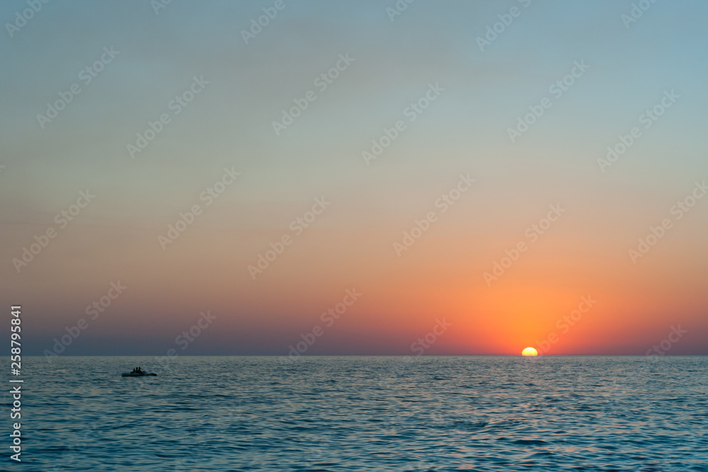 Beautiful sunset over a calm ocean or sea. Bright sunset against the sky and the sea. Sunset on the beach.