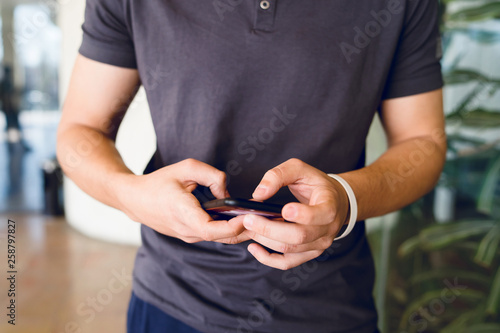 Midsection of a man using smart-phone texting message mobile phone