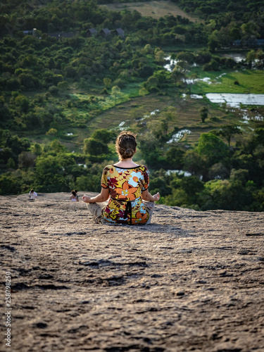 Young caucasian woman sitting and meditating on the top of the Rock Pidurangala. Sri Lanka, March 10, 2019. © Jana Kollarova