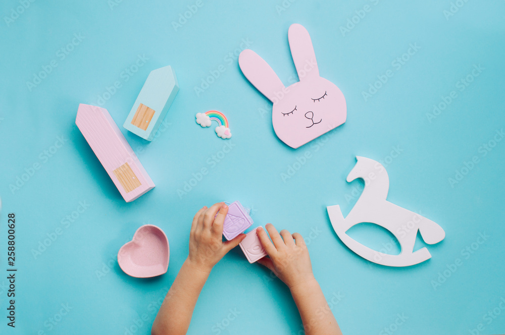 Kids hands playing with toys on blue background Kids hands playing with toys on blue background