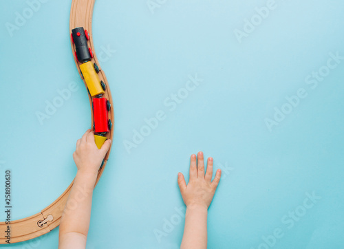 Kids hands playing with wooden toy train on blue background photo