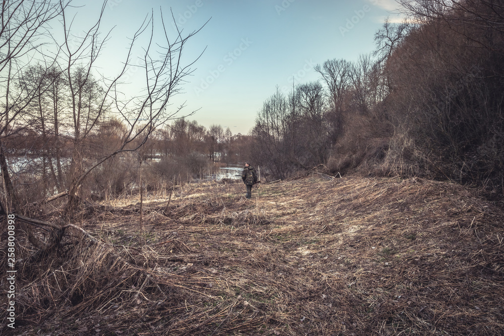 Hunter man going through forest river during spring hunting season Hunter man going through forest river during spring hunting season