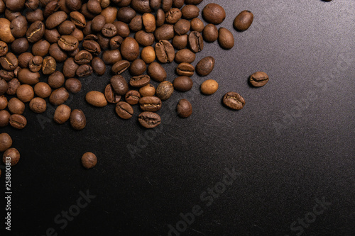 Roasted coffee beans in bulk on a black background. dark cofee roasted grain flavor aroma cafe  natural coffe shop background  top view from above  copy space