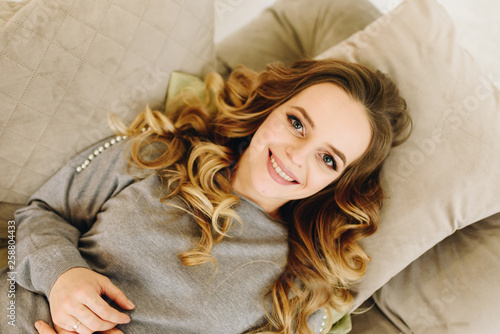 Wallpaper Mural Beautiful young caucasian European woman lying on a sofa on a bunch of pillows Torontodigital.ca