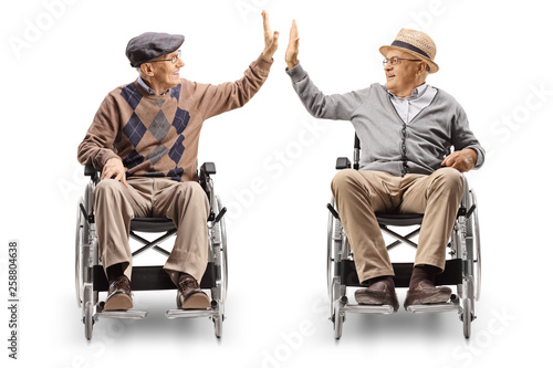 Ταπετσαρία Two senior men in wheelchairs giving high-five