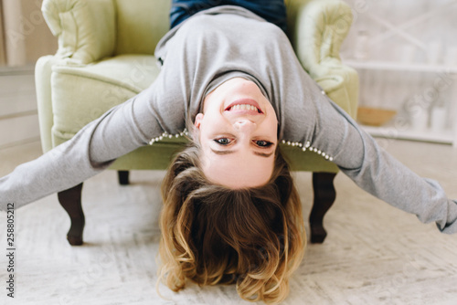 Wallpaper Mural Beautiful young caucasian European woman laying upside down on a chair. Having fun, cheerful, happy female.  Torontodigital.ca