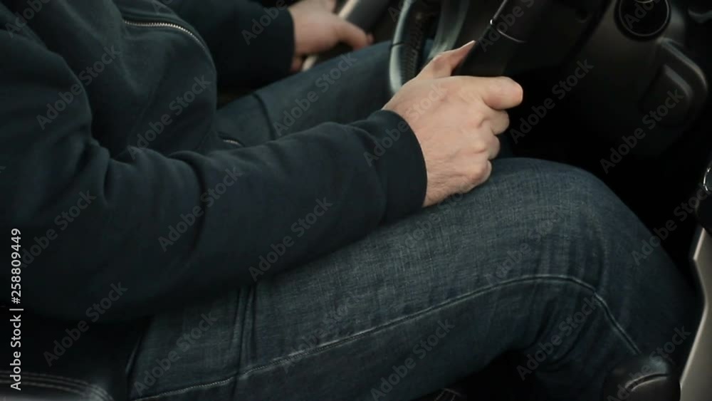 A man in jeans sit in the driver's seat of the car press the engine start button. A man in jeans sit in the driver's seat of the car press the engine start button.