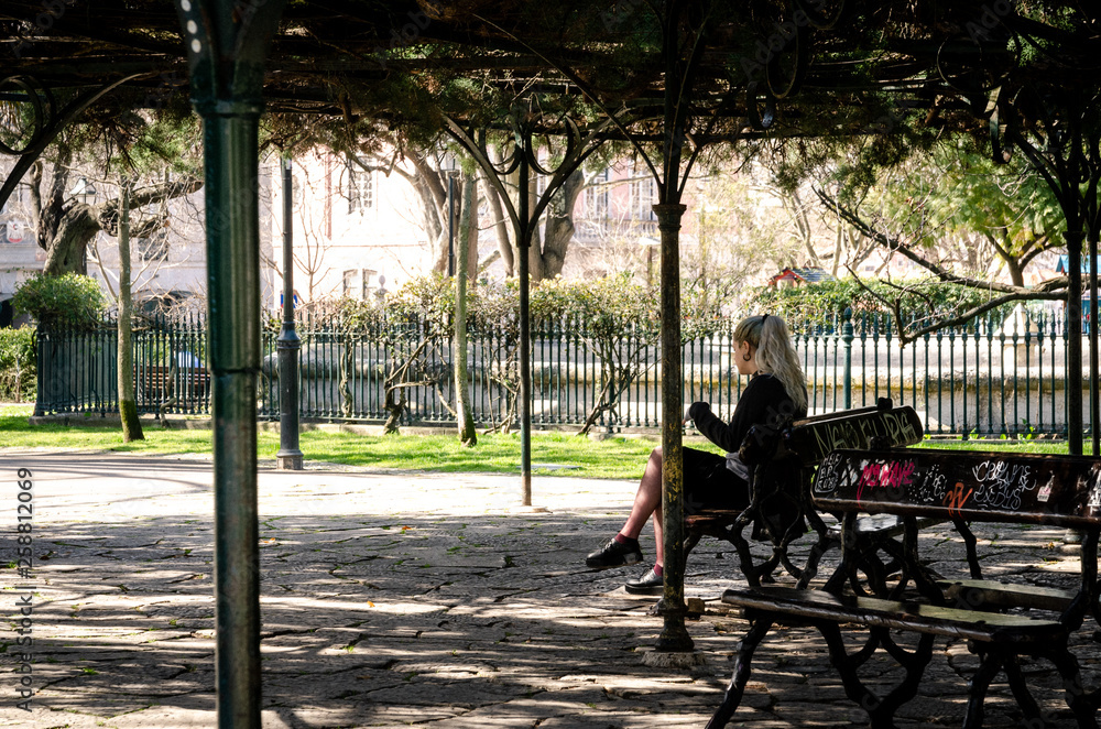 Obraz premium A young woman sitting at a bench in park