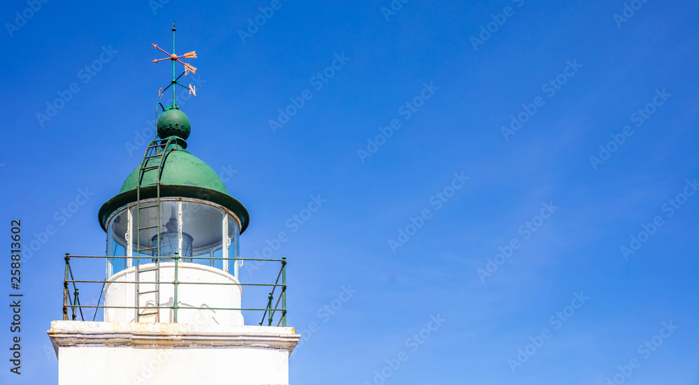 Greece. Kea island lighthouse. Lighthouse tower and weather vane on blue sky background