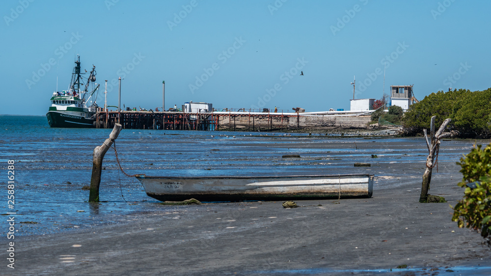 A Mexican panga fishing boat is caught on the mud flats at low tide. 