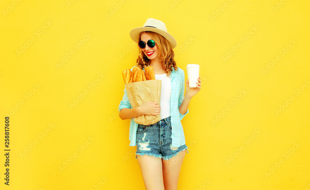 happy smiling woman holding paper bag with long white bread baguette, coffee cup, wearing straw hat, shorts on colorful yellow background happy smiling woman holding paper bag with long white bread baguette, coffee cup, wearing straw hat, shorts on colorful yellow background