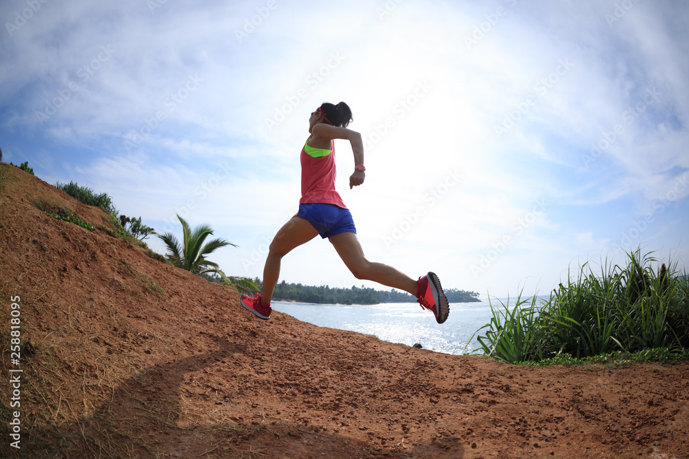 Woman trail runner running on seaside hills Woman trail runner running on seaside hills