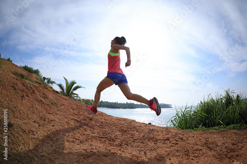 Woman trail runner running on seaside hills